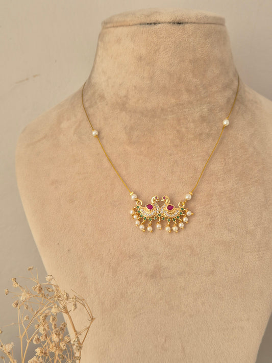 Detailed view of an antique gold choker necklace with pearl clusters and ruby-pink drop stones, alongside matching stud earrings