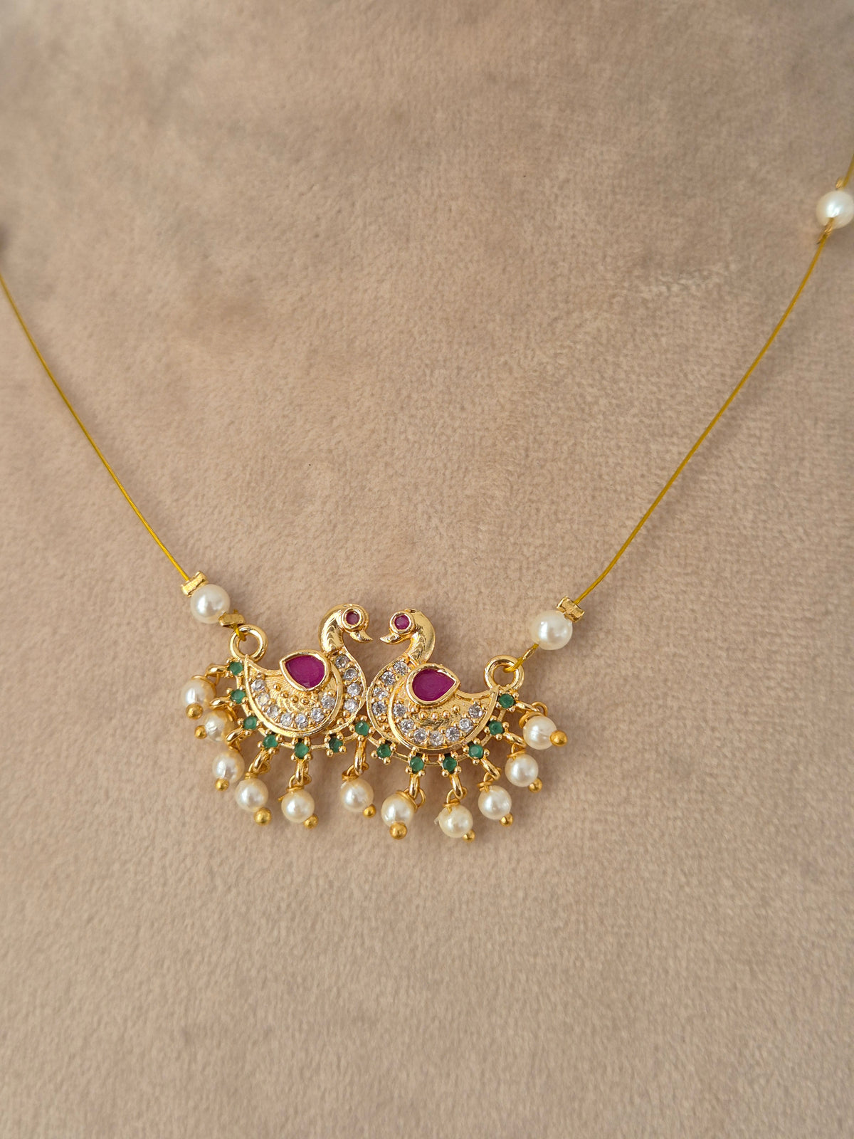 Antique gold traditional jewelry set featuring a wide choker necklace with ruby-pink drop stones, matching chandelier earrings