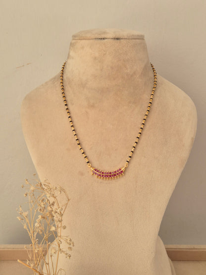 Antique gold mangalsutra featuring a traditional pendant with ruby-pink drop stones, black bead chain