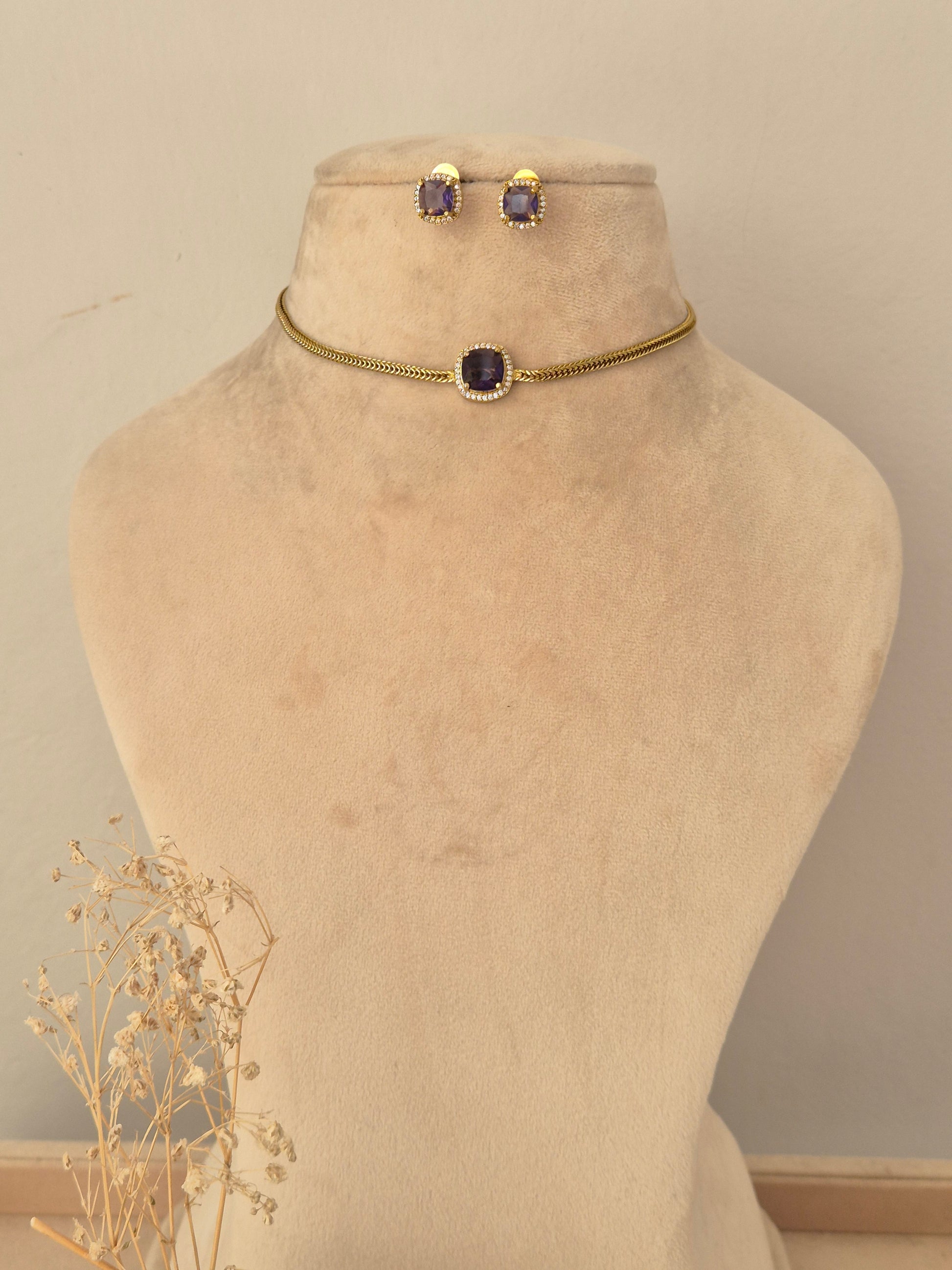 Antique gold long-chain mangalsutra featuring a detailed floral-motif pendant with ruby-pink teardrop stones, black bead strands, and matching stud earrings