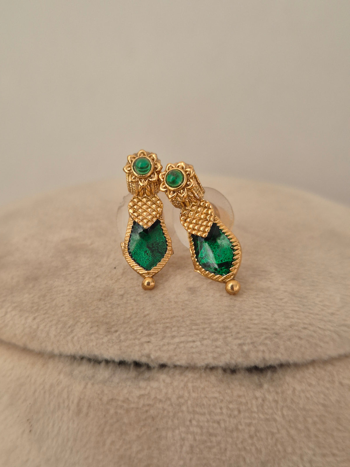 Close-up of antique gold temple choker with Goddess Laxmi coin motifs and emerald-green stone drops