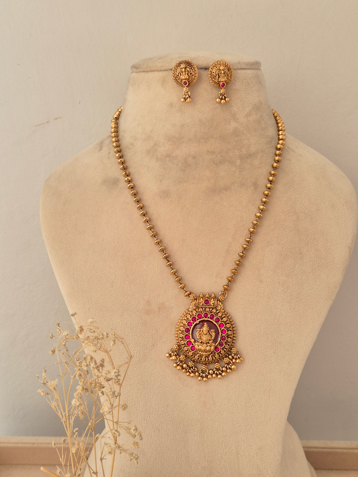 Antique gold-plated round temple earrings with goddess motif, red stone accent, and dangling gold bead clusters