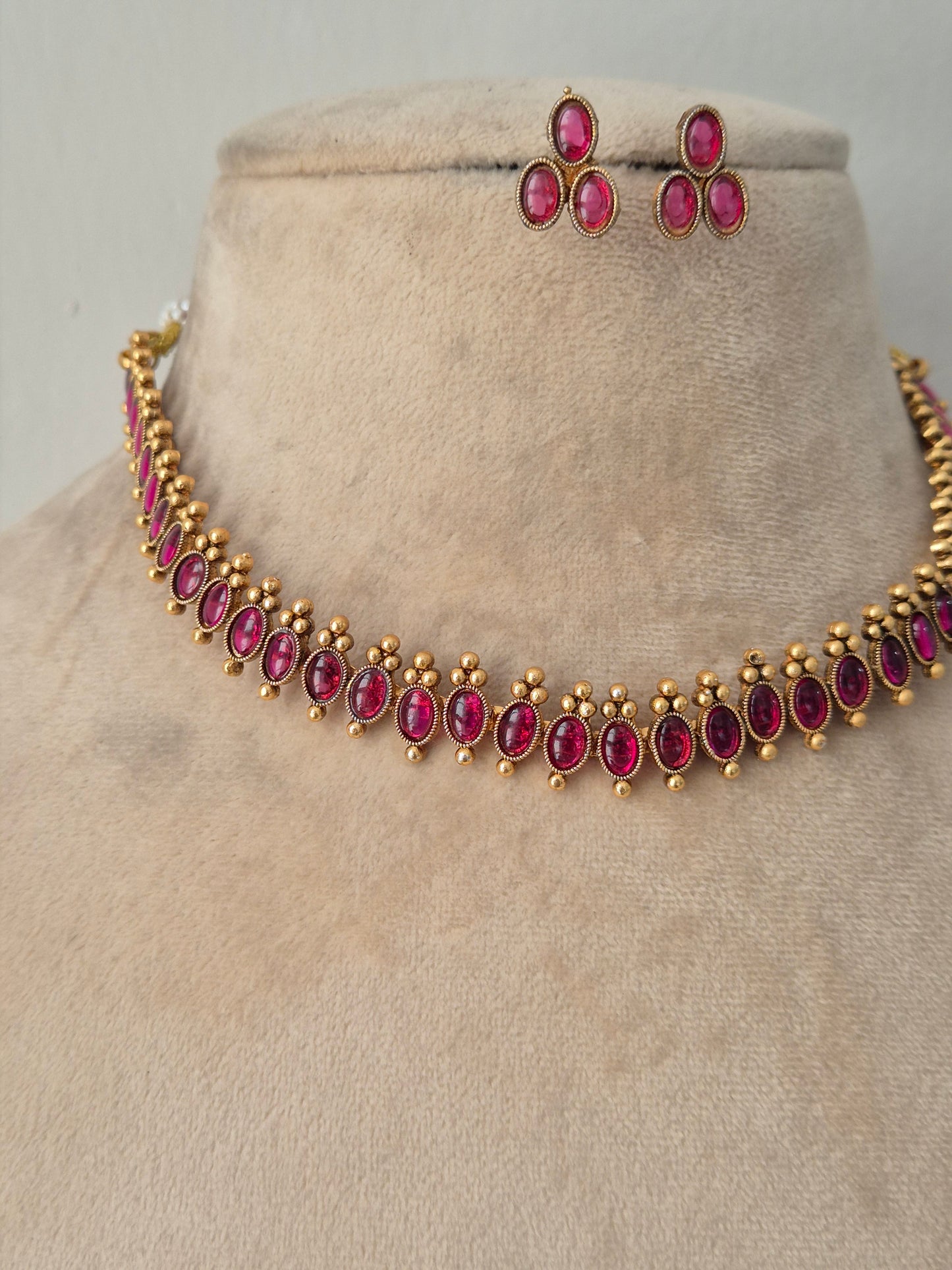 Antique gold-finished choker necklace studded with oval and marquise ruby-pink stones, framed by delicate gold bead drops, paired with matching teardrop stud earrings
