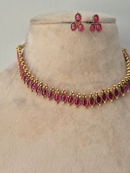 Antique gold-finished choker necklace studded with oval and marquise ruby-pink stones, framed by delicate gold bead drops, paired with matching teardrop stud earrings