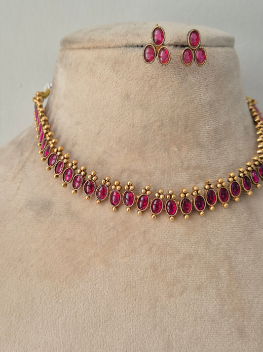Antique gold-finished choker necklace studded with oval and marquise ruby-pink stones, framed by delicate gold bead drops, paired with matching teardrop stud earrings