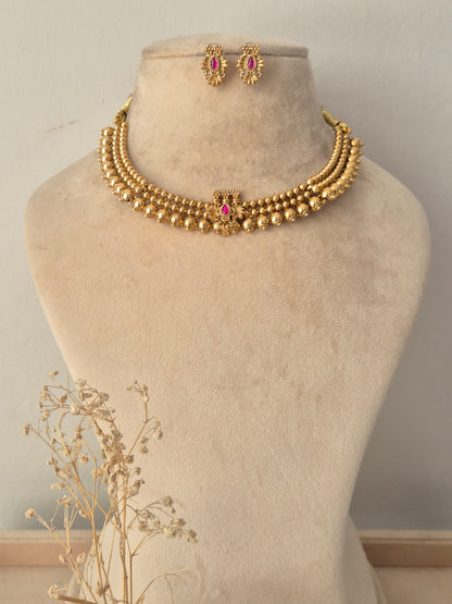 Antique gold three-strand bead necklace featuring a pink stone central pendant and matching stud earrings