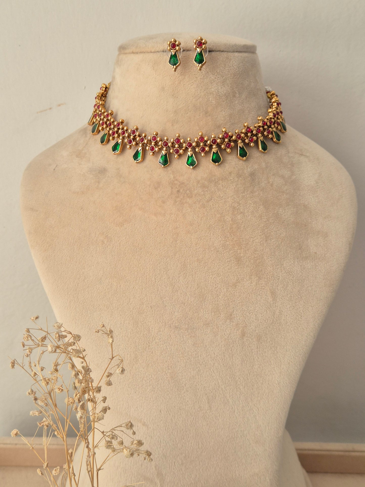 Gold-toned choker necklace set with green teardrop stone dangles, ruby-red stone accents, and matching small drop earrings
