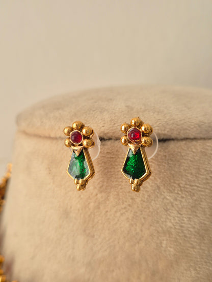 Option 1 (Short): Close-up of antique gold stud earrings featuring floral tops set with ruby-red stones and emerald-green drops