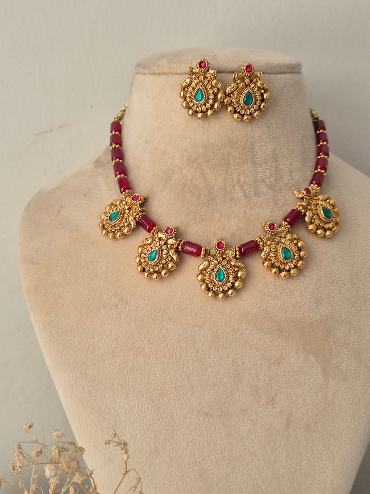 Traditional Indian antique gold jewellery set featuring a necklace of faceted ruby-red beads strung with ornate gold pendants containing teardrop turquoise-green stones