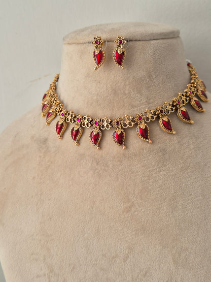 Traditional gold-toned choker with ruby-red stone dangles and matching drop earrings on a display bust