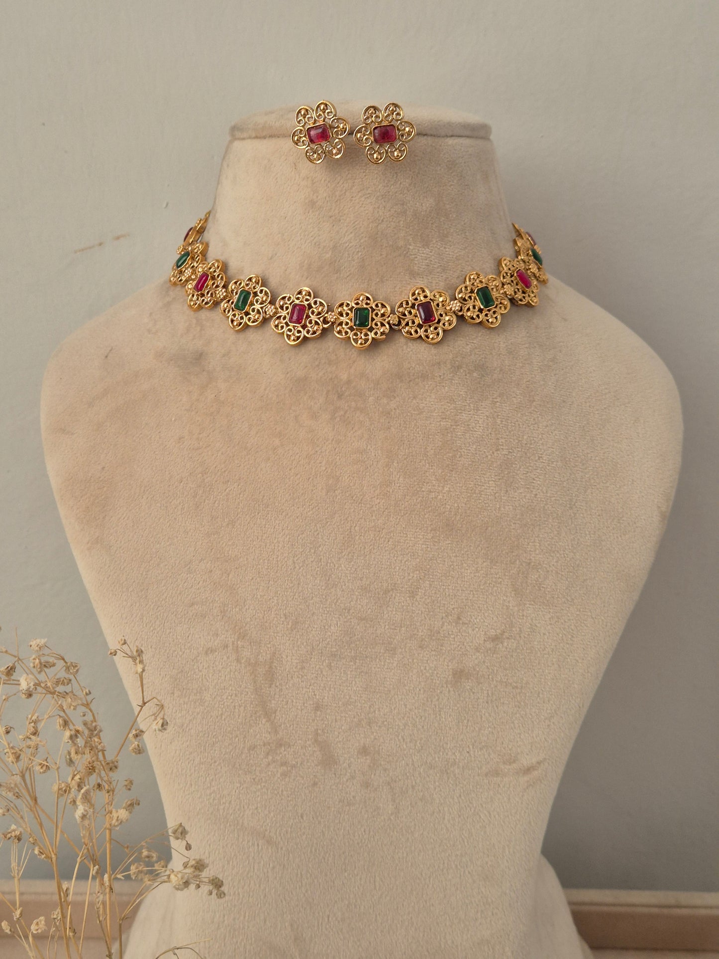 Antique gold floral choker necklace set with alternating ruby-red and emerald-green stone centers and matching floral stud earrings