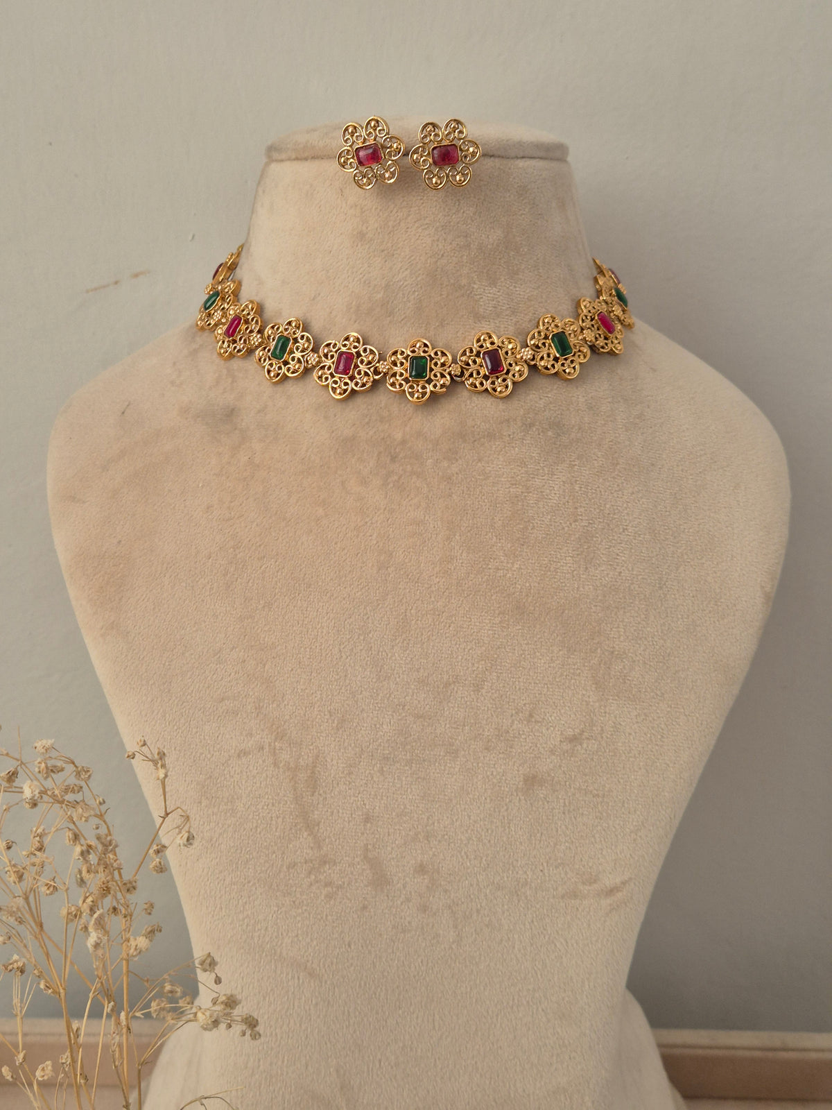 Antique gold floral choker necklace set with alternating ruby-red and emerald-green stone centers and matching floral stud earrings