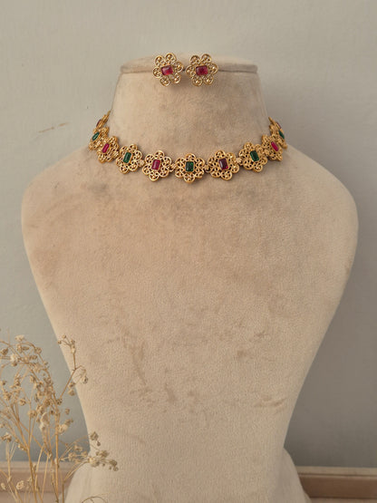 Antique gold floral choker necklace set with alternating ruby-red and emerald-green stone centers and matching floral stud earrings