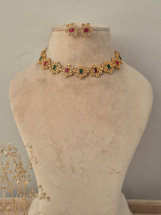 Antique gold floral choker necklace set with alternating ruby-red and emerald-green stone centers and matching floral stud earrings