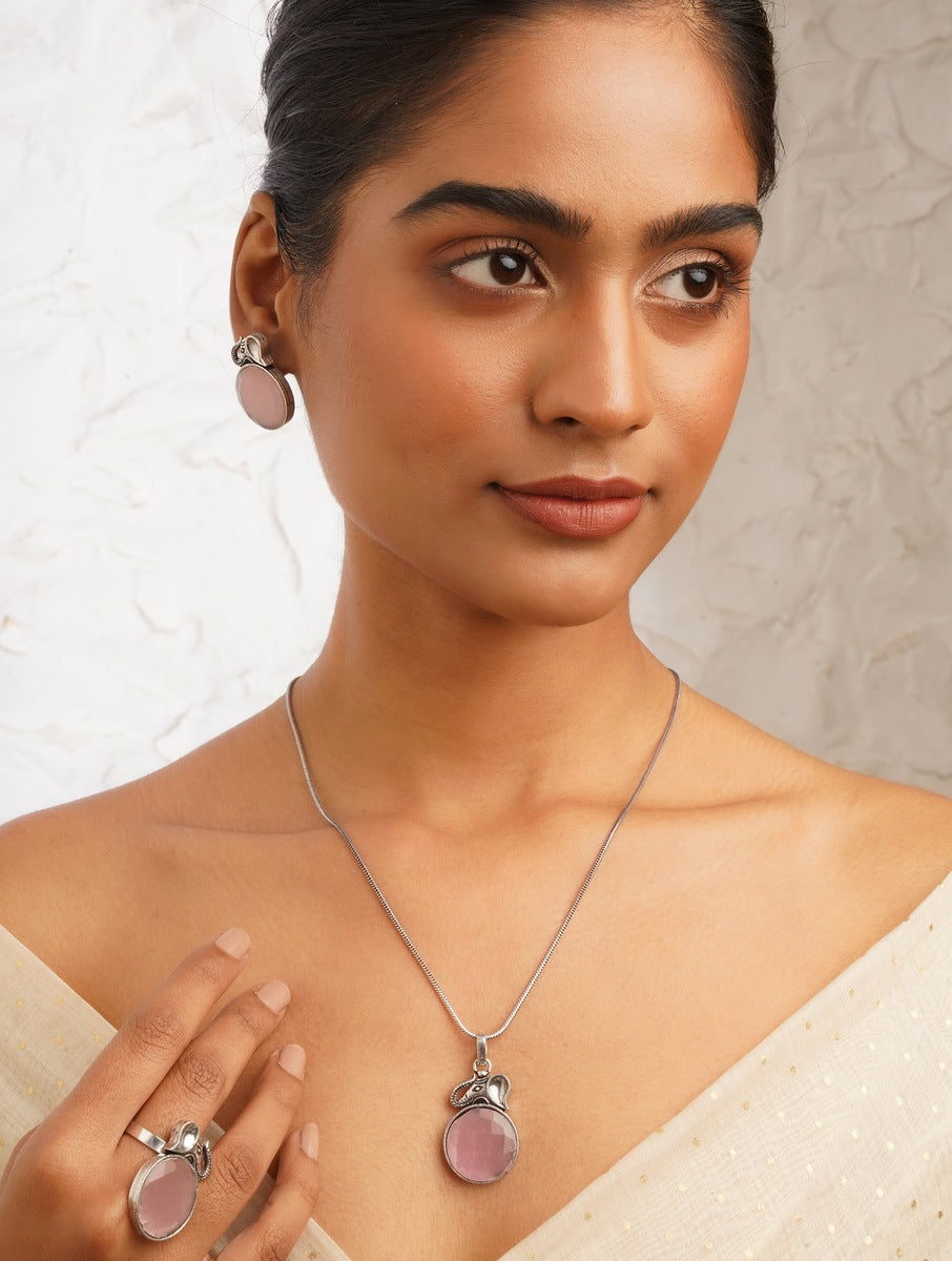 Pink and silver necklace, earrings, ring set on soft background