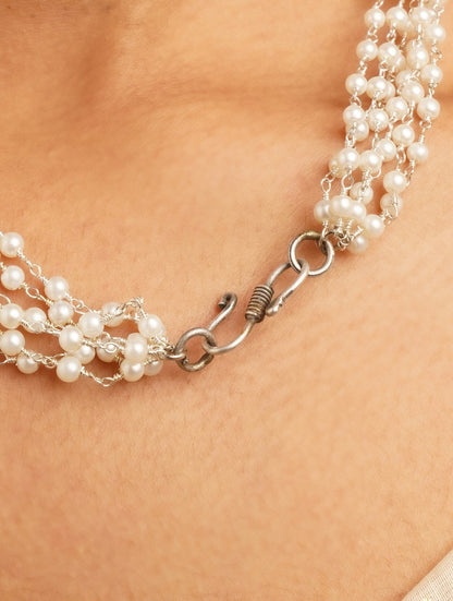 Gold, white, silver beaded necklace set laid out on dark background