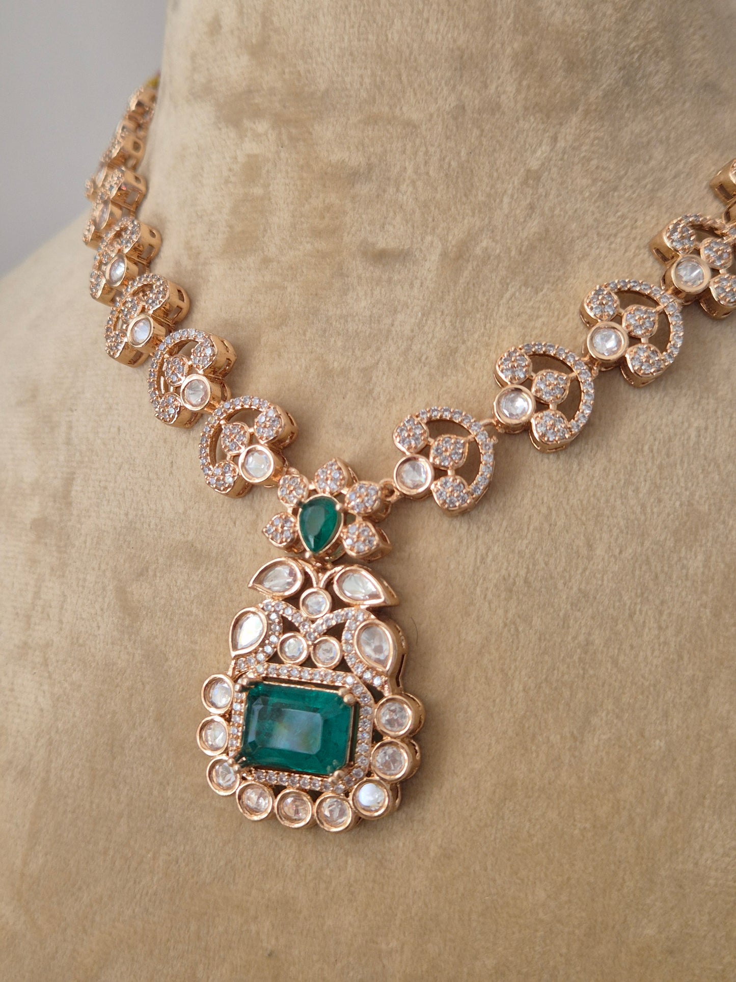 Rose-Gold toned necklace with a large emerald green pendant surrounded by clear crystals by naitri.in