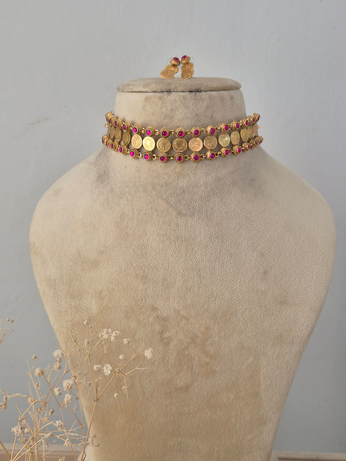 Aakhi golden choker necklace set with ruby-colored stone accents and matching stud earrings by Naitri.in