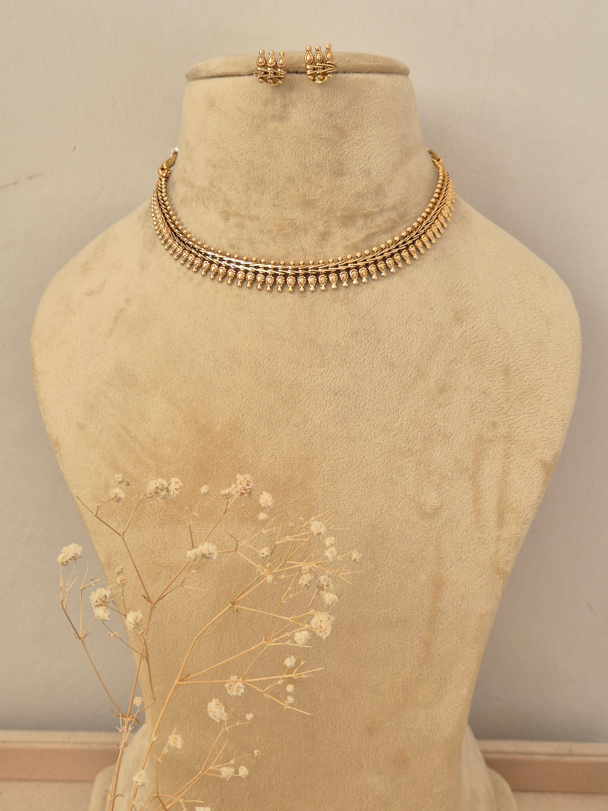 A gold-toned multi-strand beaded choker necklace with matching small stud earrings at the top by naitri.in