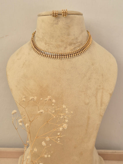 A gold-toned multi-strand beaded choker necklace with matching small stud earrings at the top by naitri.in