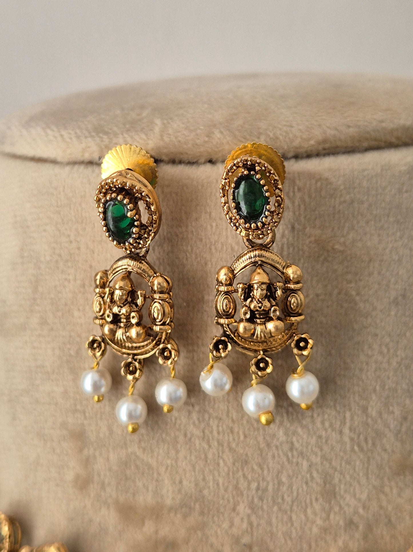 Antique gold-plated earring featuring intricate Indian artisanal metalwork, oval-cut green stones, and delicate hanging white pearls, by naitri.in