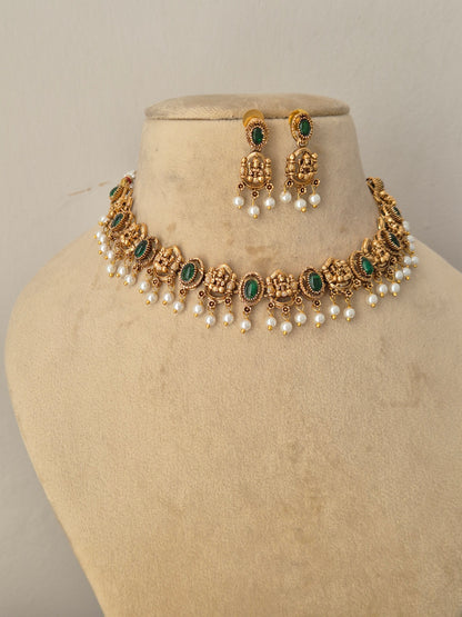 Handcrafted antique gold statement jewelry set showcasing vibrant green embellishments and seed pearls, traditional Indian style golden brass alloy emerald choker necklace and earring set by naitri.in