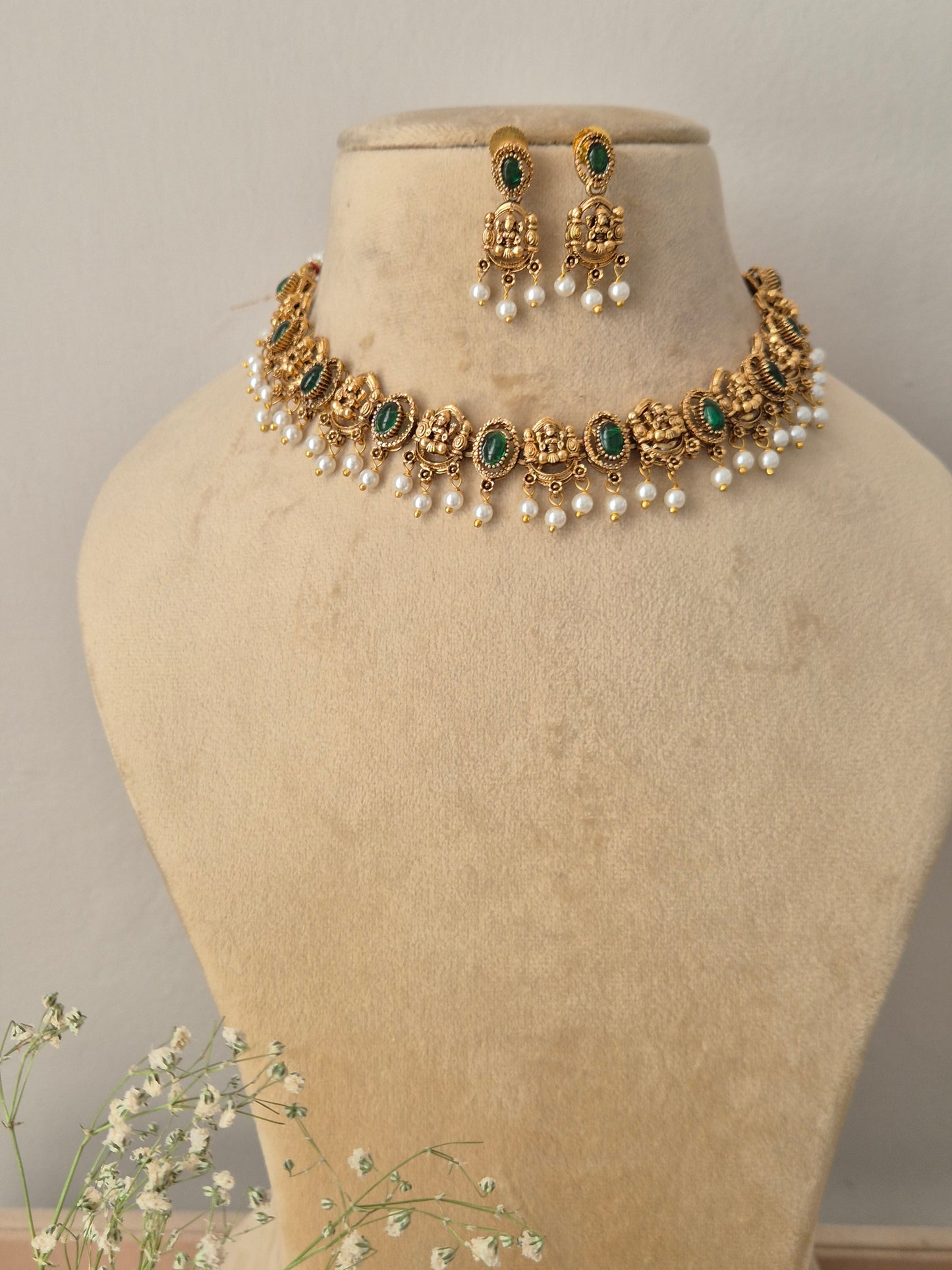 Antique gold choker necklace with emerald-green gemstone accents and dangling pearls, with matching earrings by naitri.in