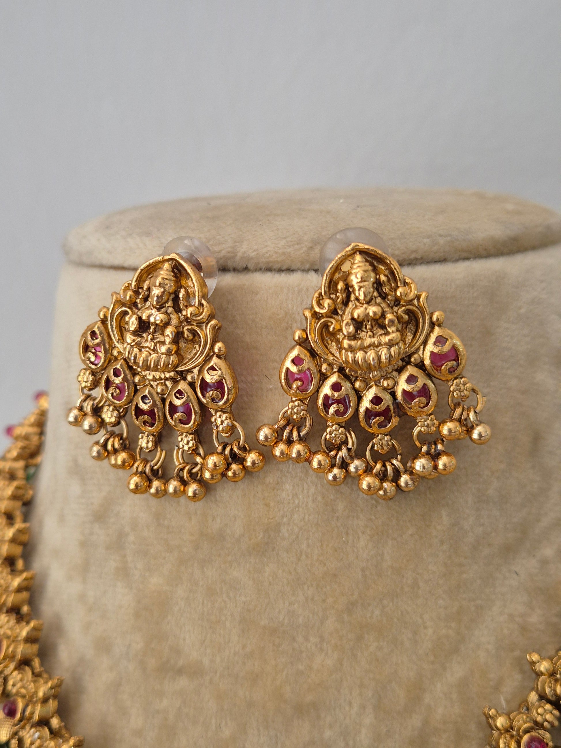 Gold-plated temple jewelry with a Goddess Lakshmi pendant, colorful gemstones, and matching jhumka earrings by naitri.in