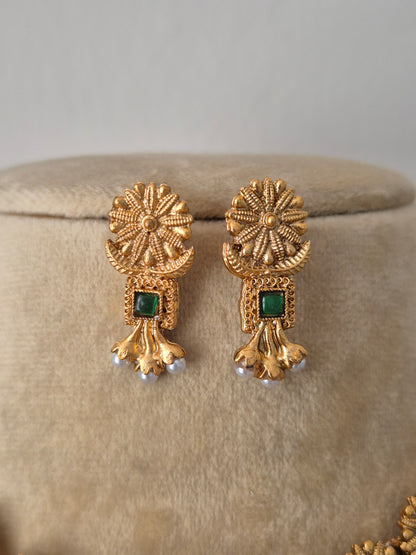 Antique gold earrings earrings and small green gemstones intricate textured circular engravings, small green stone embellishments, and delicate white hanging pearls by naitri.in