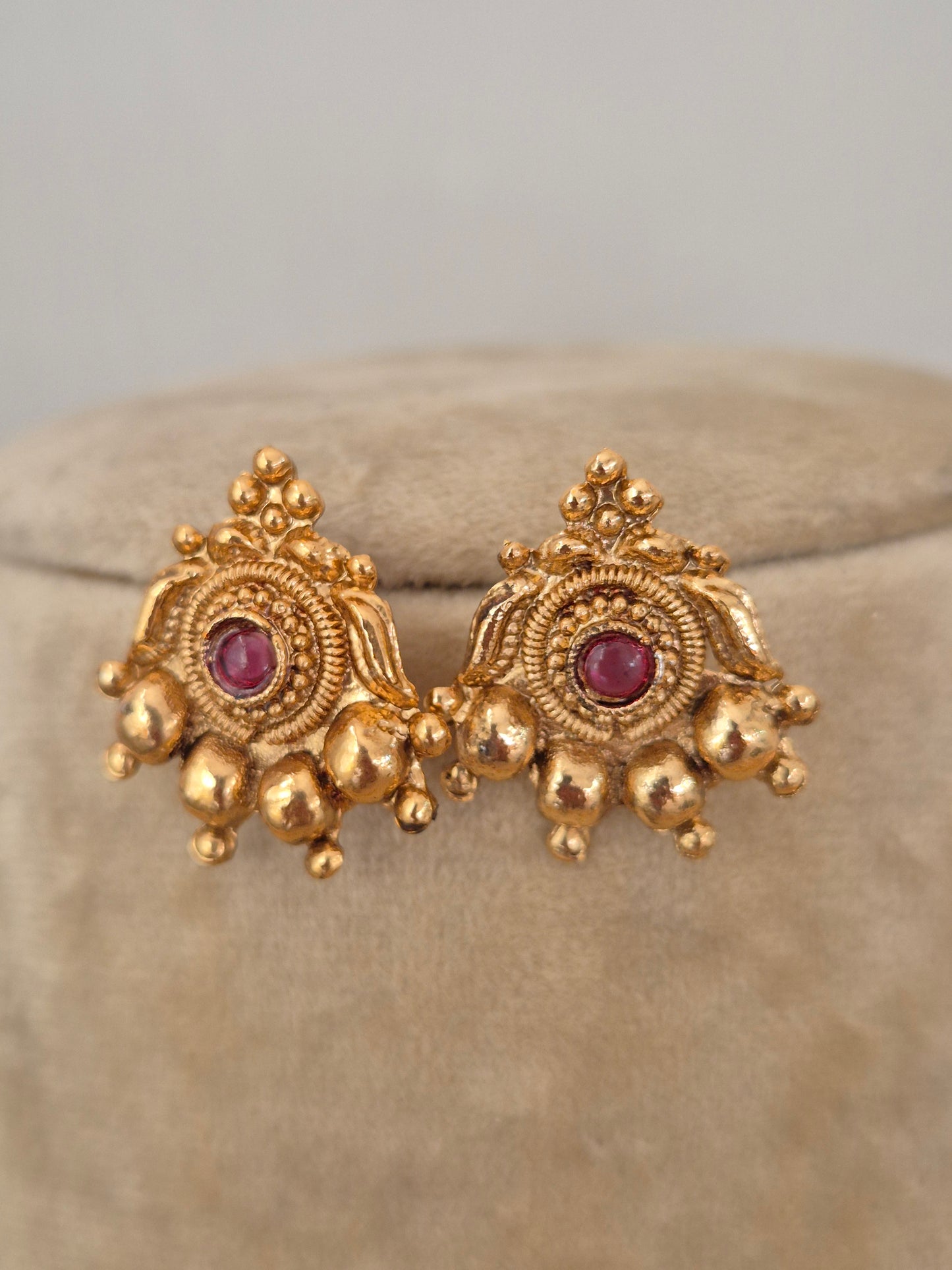 Handcrafted gold stud earrings featuring red and green stones with gold bead fringes by naitri.in