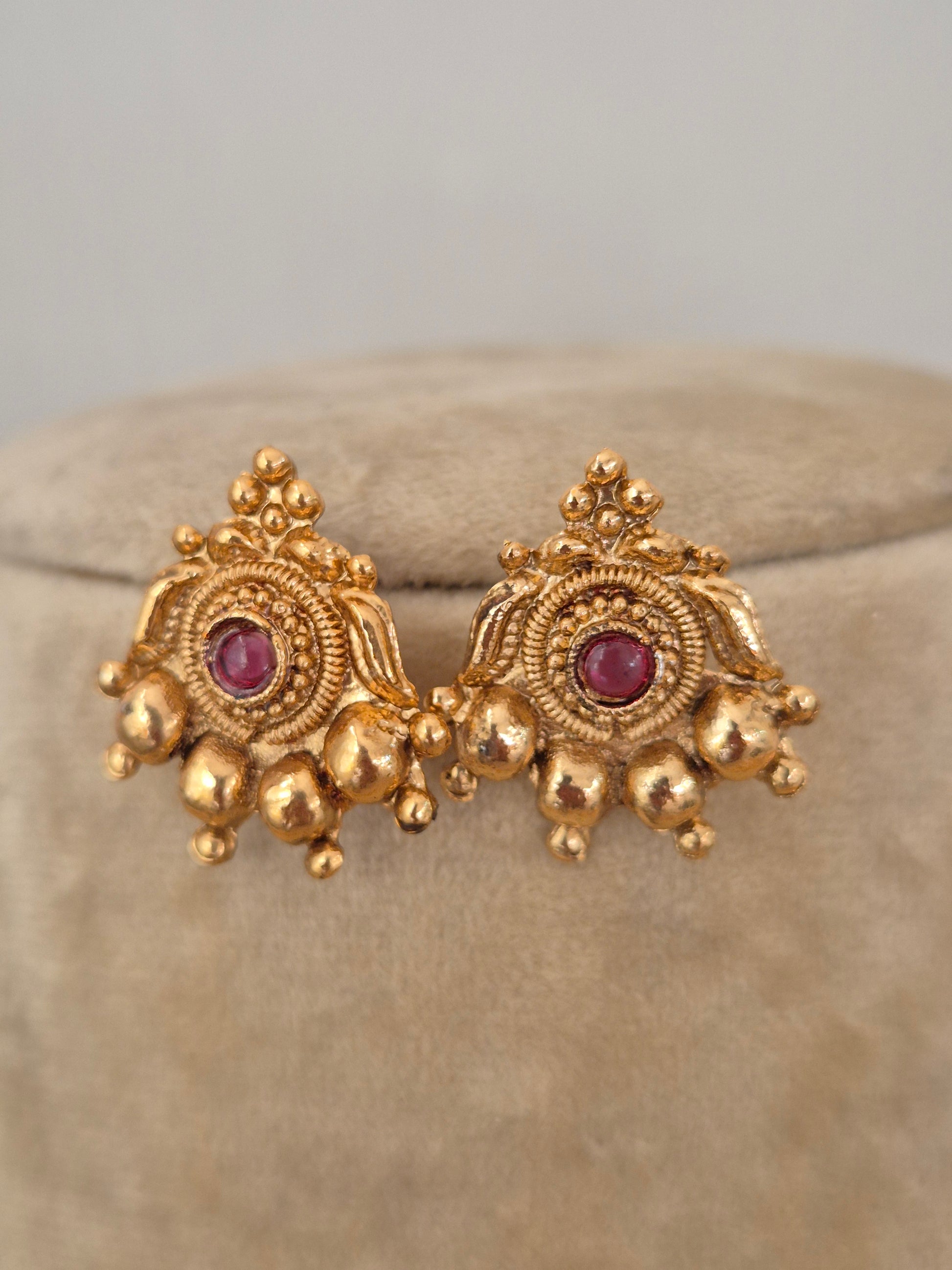 Handcrafted gold stud earrings featuring red and green stones with gold bead fringes by naitri.in