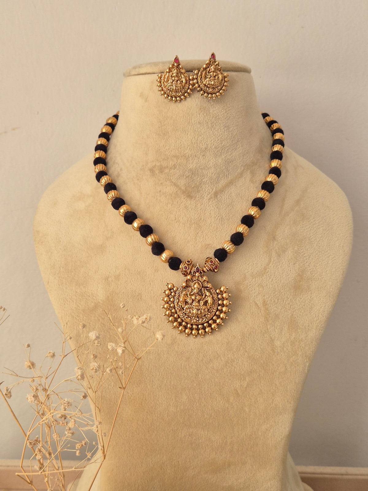 Akansha Necklace Set featuring a traditional gold mangalsutra-style black beaded chain with an intricate temple pendant and matching earrings, displayed on a mannequin by Naitri.in