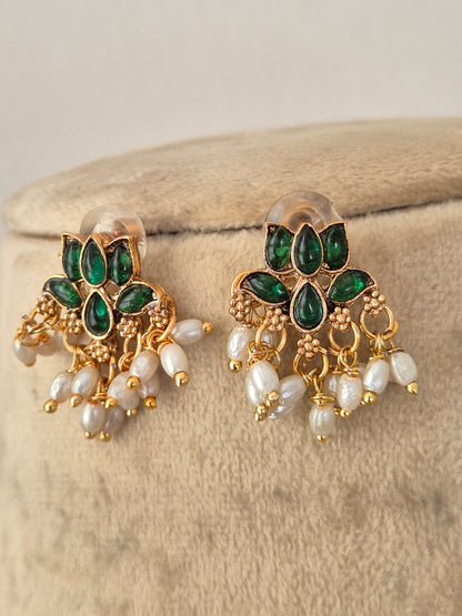A pair of gold-plated Indian jhumka earrings with green stone accents and white pearl-like beads, by naitri.in