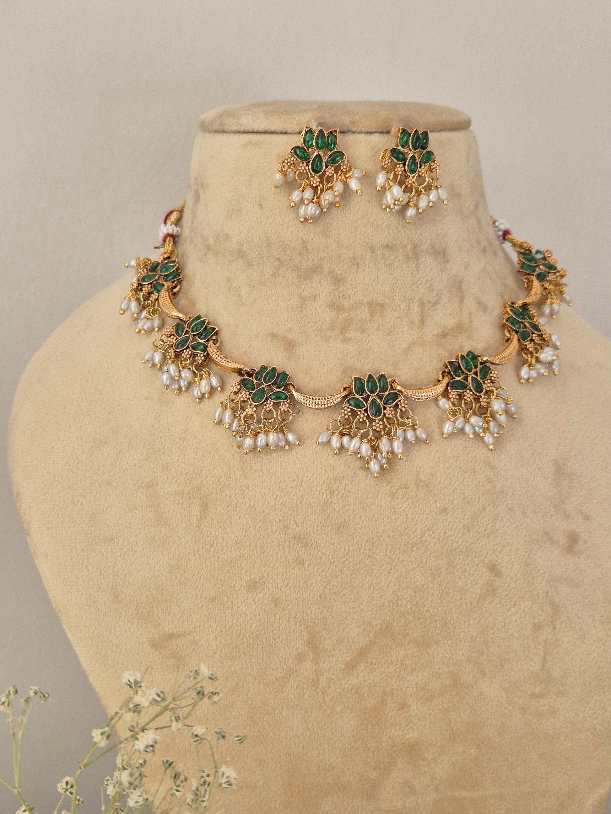 Akshara Necklace Set by Naitri featuring an ethnic gold-plated choker and matching traditional statement earrings with green stones and pearls for festive occasions by naitri.in