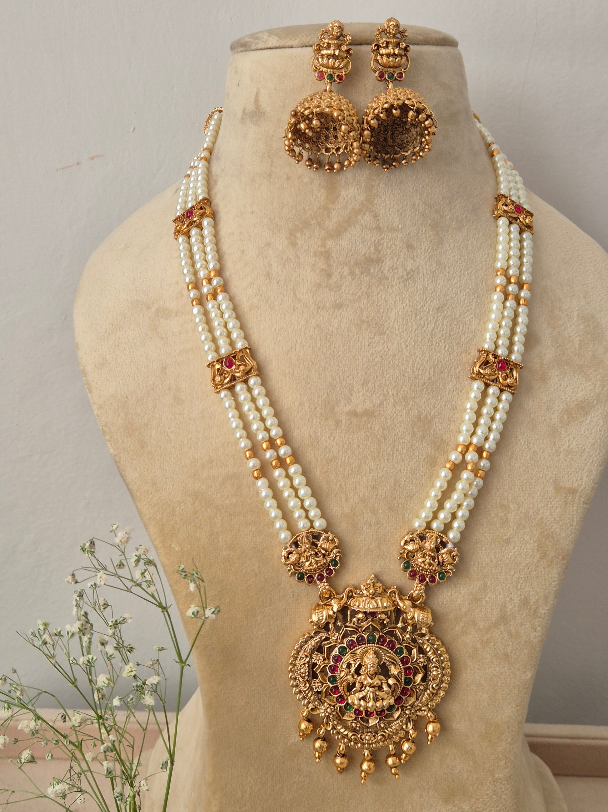 Handcrafted ethnic gold-plated pendant necklace with elegant pearl strands and temple jewelry motifs Indian style traditional pearl chain choker necklace and jhumka earring set from the NAITRI by naitri.in