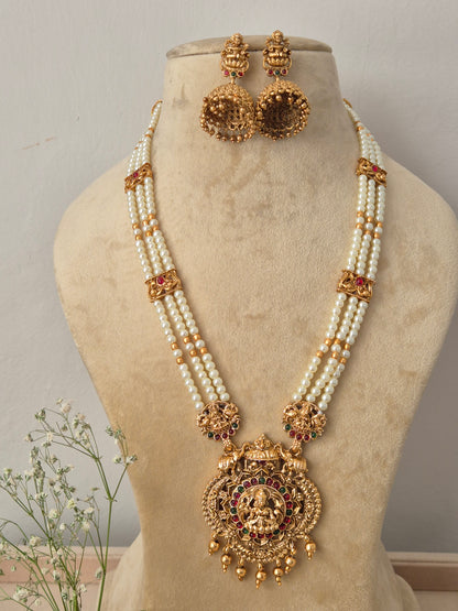 Traditional multi-strand pearl necklace with a large antique gold deity pendant and matching jhumka earrings, by naitri.in