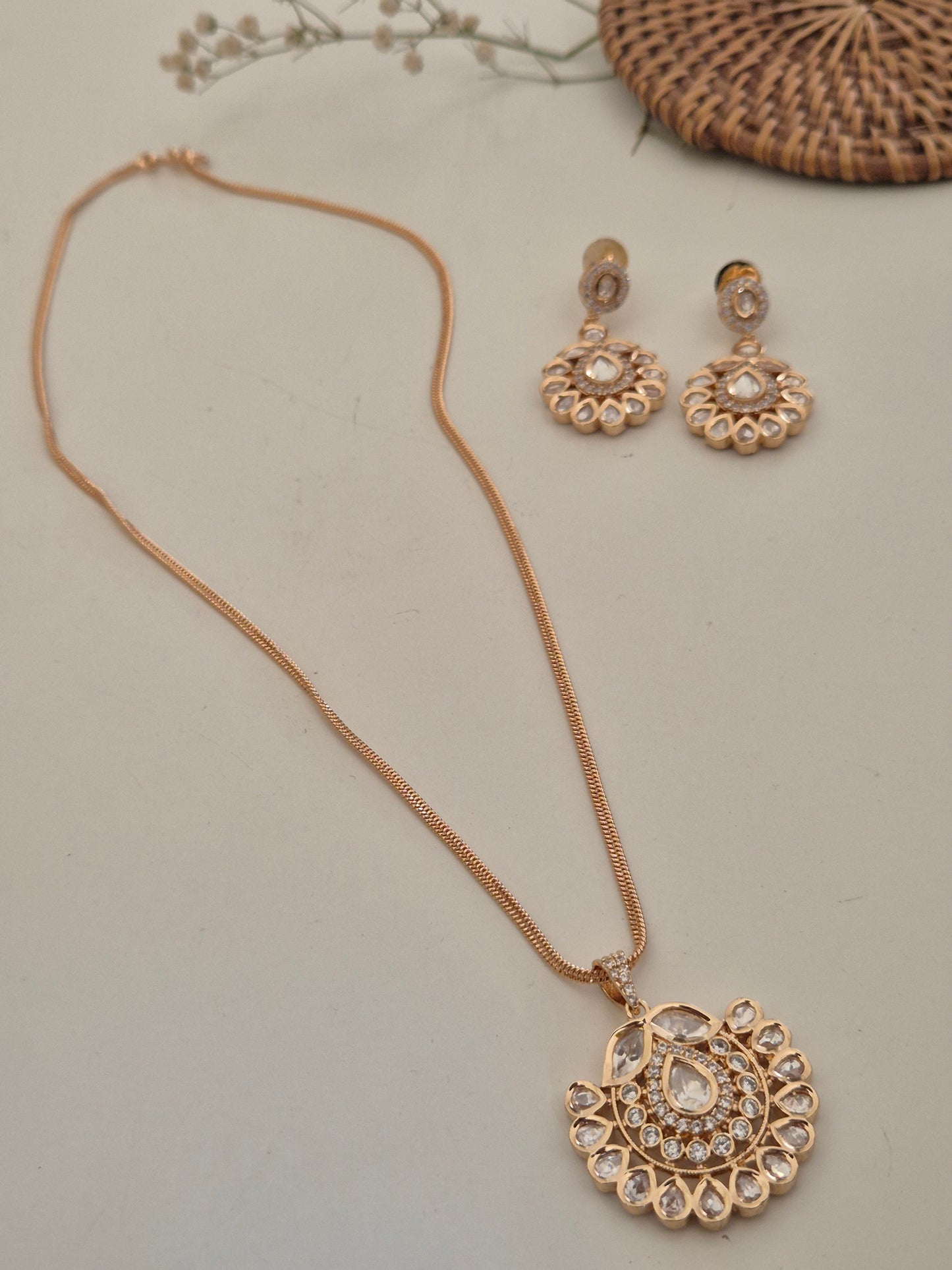 Intricate pendant necklace with a central teardrop stone surrounded by shimmering American Diamonds, paired with matching statement earrings by naitri.in