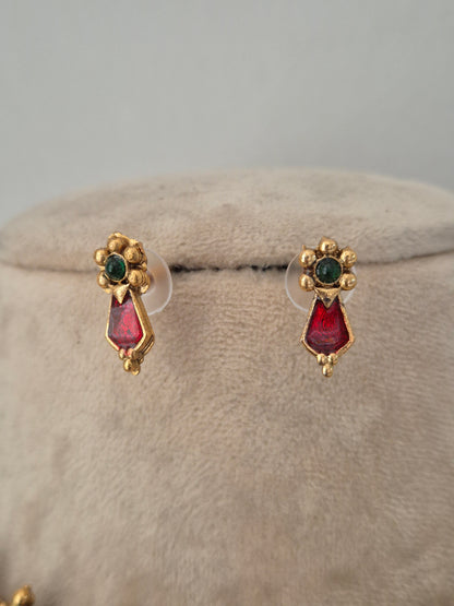 A pair of gold-toned stud earrings with green oval stones at the top and red teardrop-shaped stones below, by naitri.in