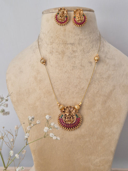 Handcrafted gold-plated brass necklace featuring a traditional Indian pendant with red stone accents and matching floral stud earrings by naitir.in