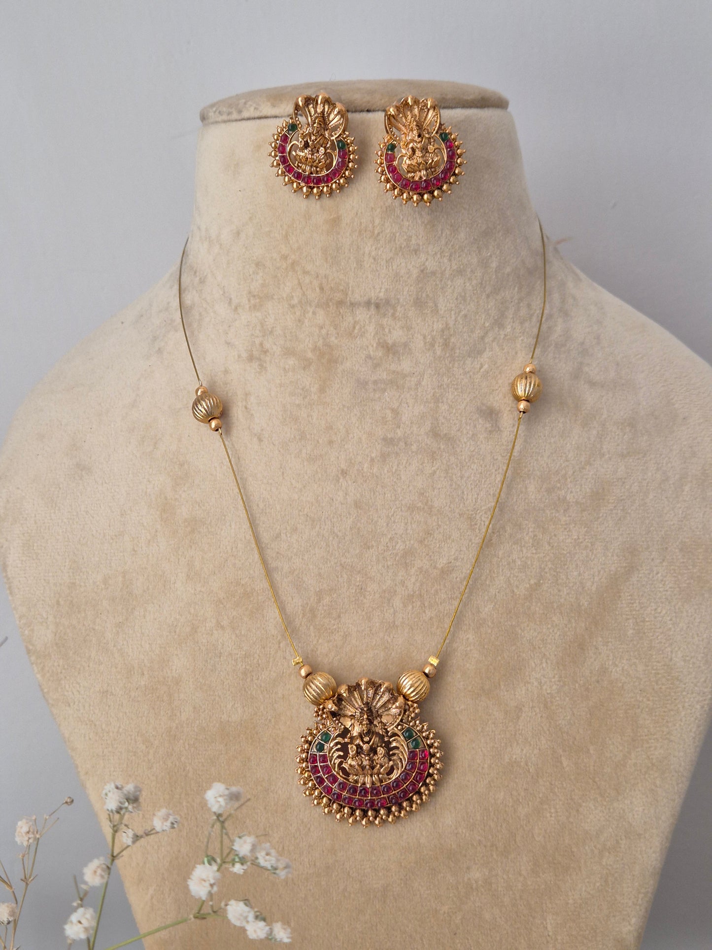 handmade Amayra necklace set from the Naitri collection, featuring a brass alloy pendant with intricate metalwork and ruby-red stones on a delicate thin chain by naitri.in