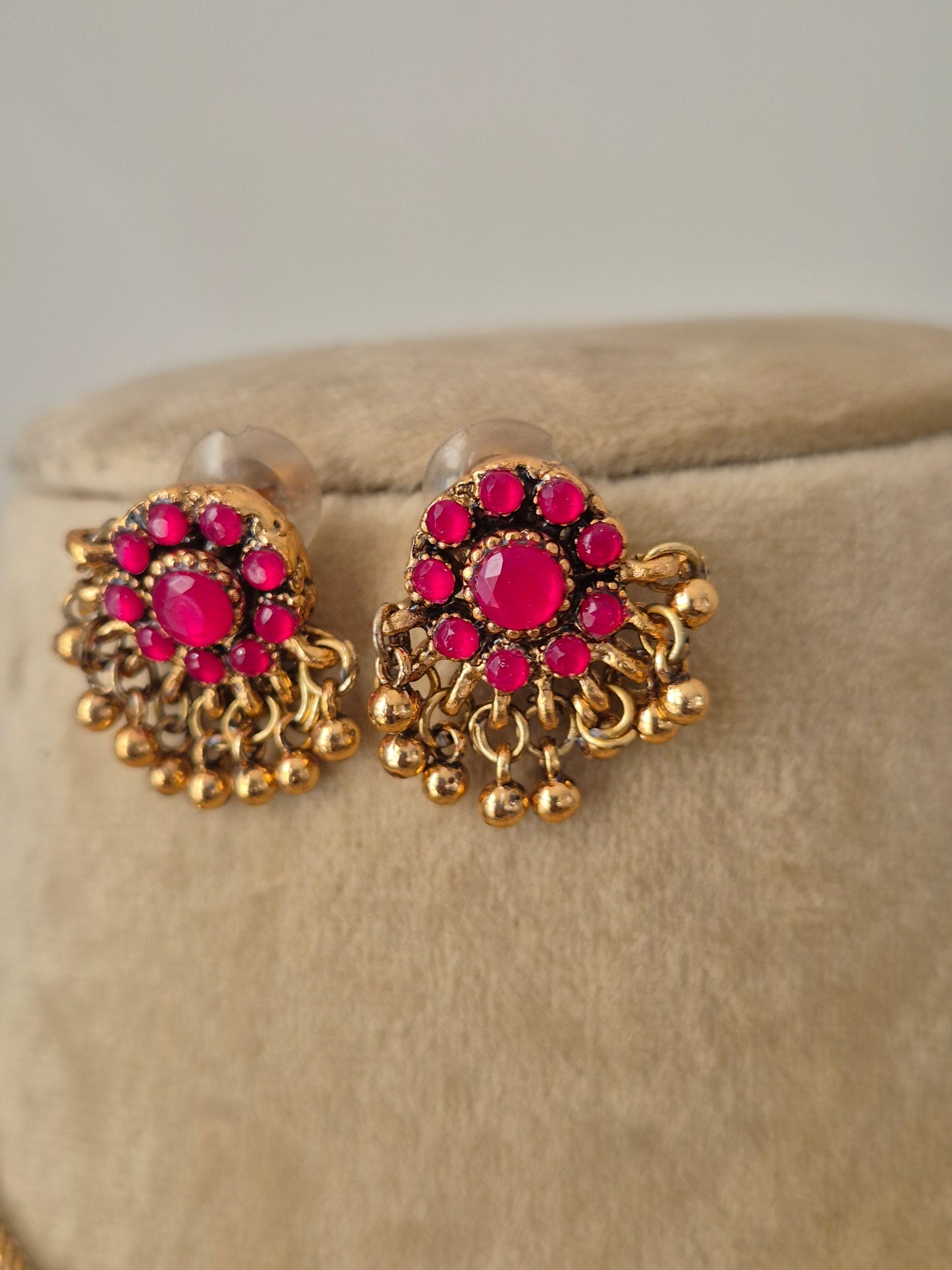 A gold minimalist chain with bright pink floral pendants and matching ethnic earrings by naitri.in
