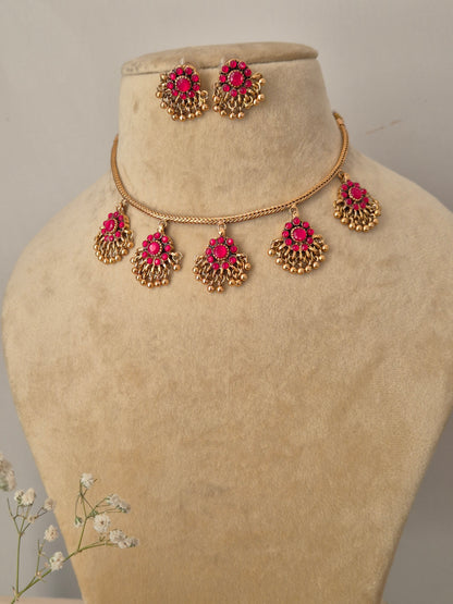 Traditional Indian imitation jewelry set in gold and pink stone, featuring a tiered pendant design on a delicate gold chain by naitri.in
