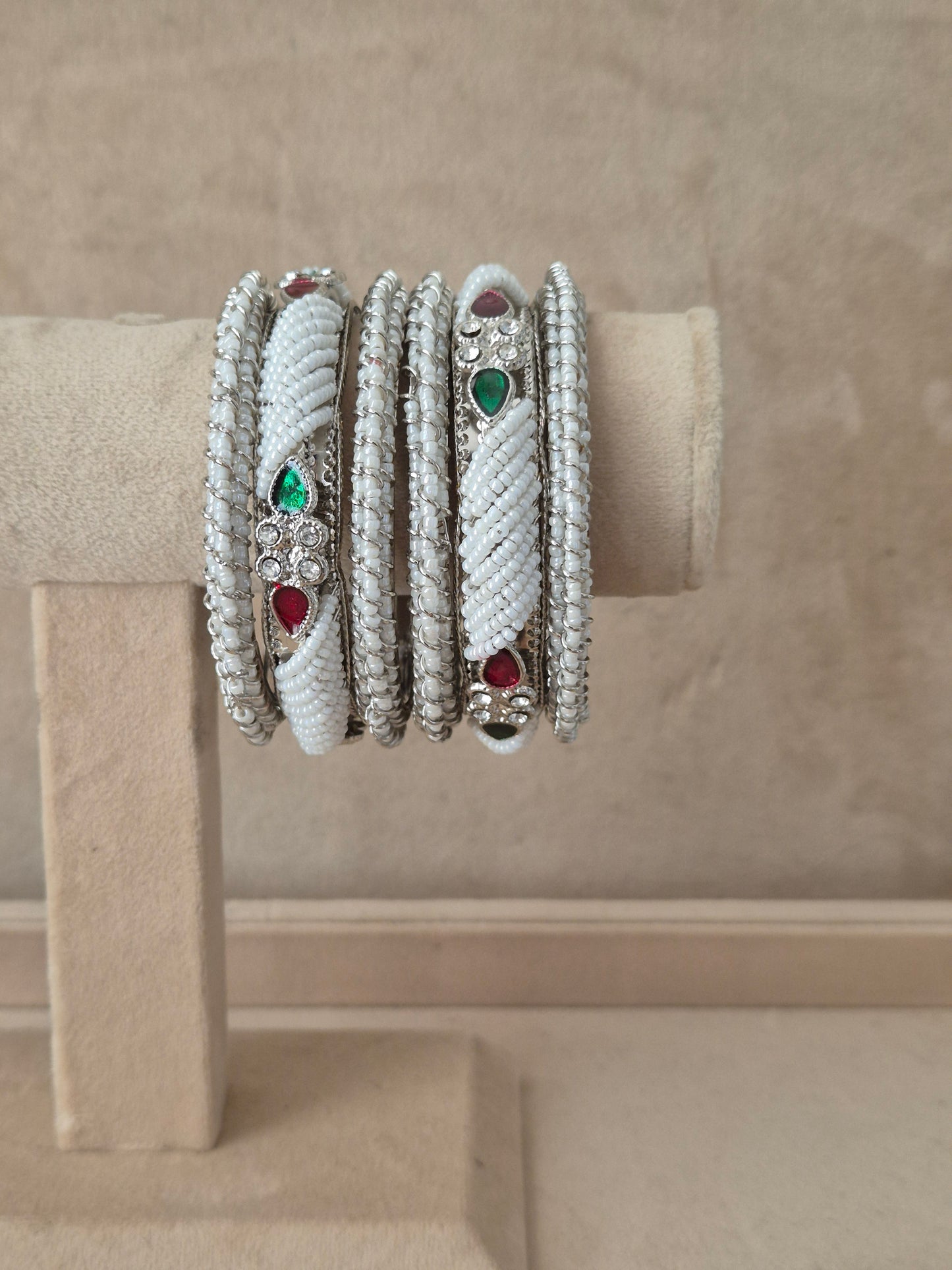Pair of antique silver-toned traditional Indian bangles featuring intricate floral open-work patterns, a central round ruby red gemstone, and detailed rope-textured borders, by naitri.in