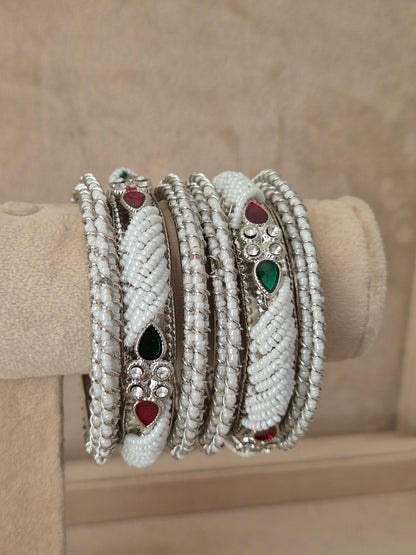 Statement silver bridal bangles with intricate cutout filigree details, a central red gemstone setting, and a textured antique finished by naitri.in