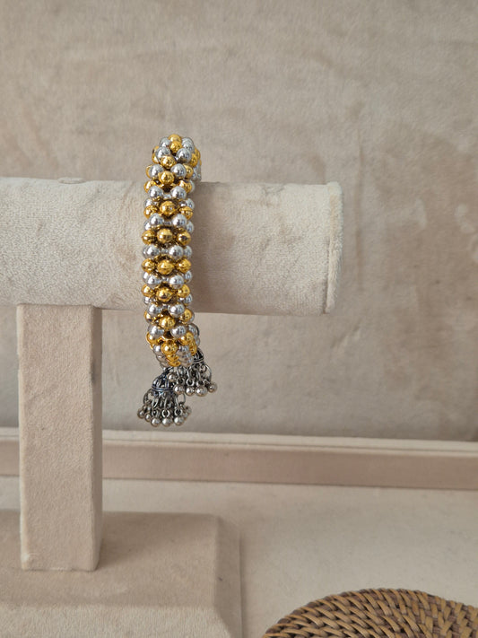 Dual-tone Amukta bangle bracelet featuring alternating rows of textured gold and silver beads with dangling oxidized silver jhumka charms by naitri.in