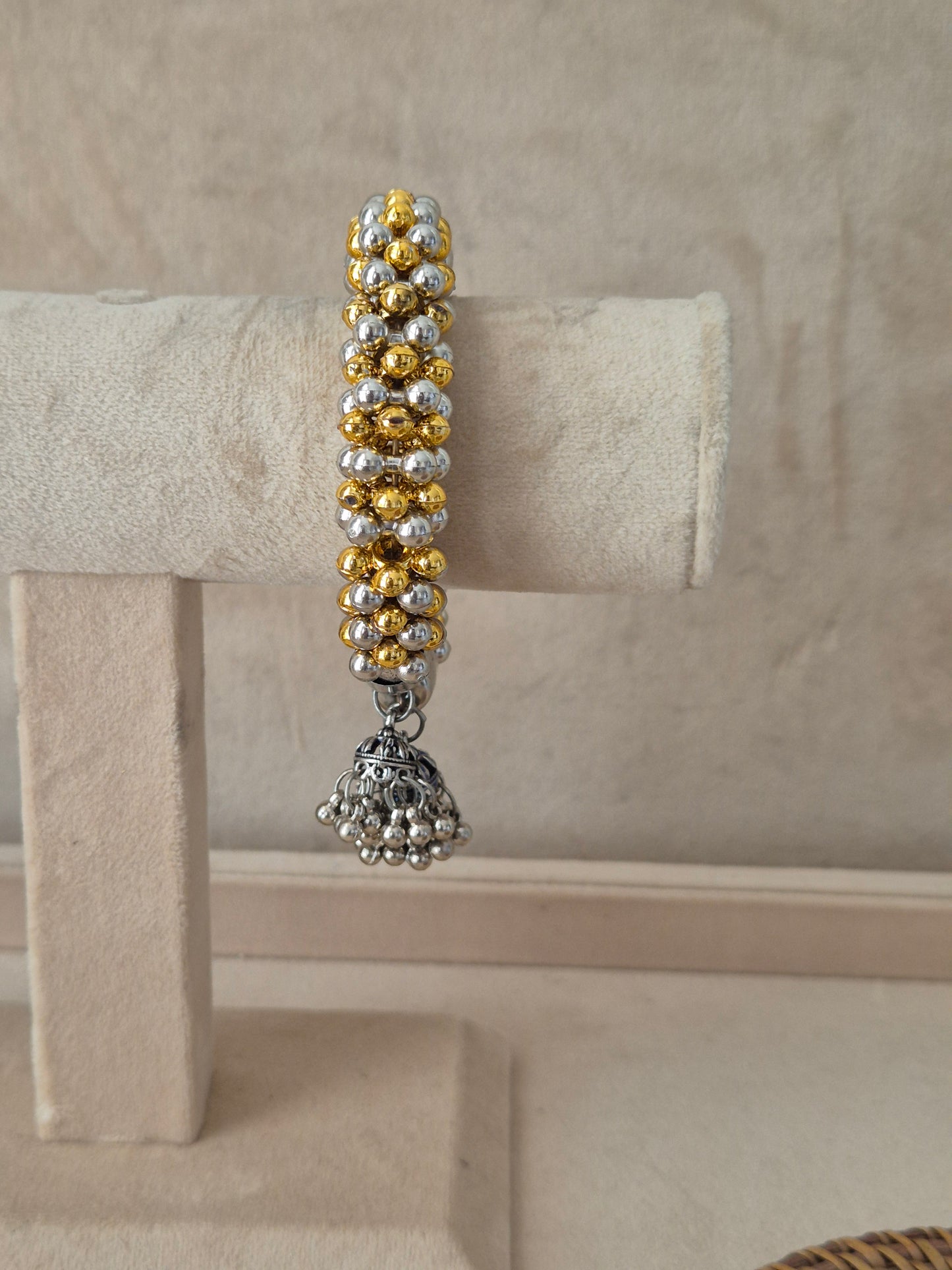 Statement gold and silver-plated festive Kada bangle featuring intricate rows of metallic beads and hanging bell charms by naitri.in