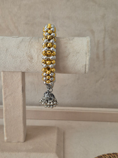 Statement gold and silver-plated festive Kada bangle featuring intricate rows of metallic beads and hanging bell charms by naitri.in