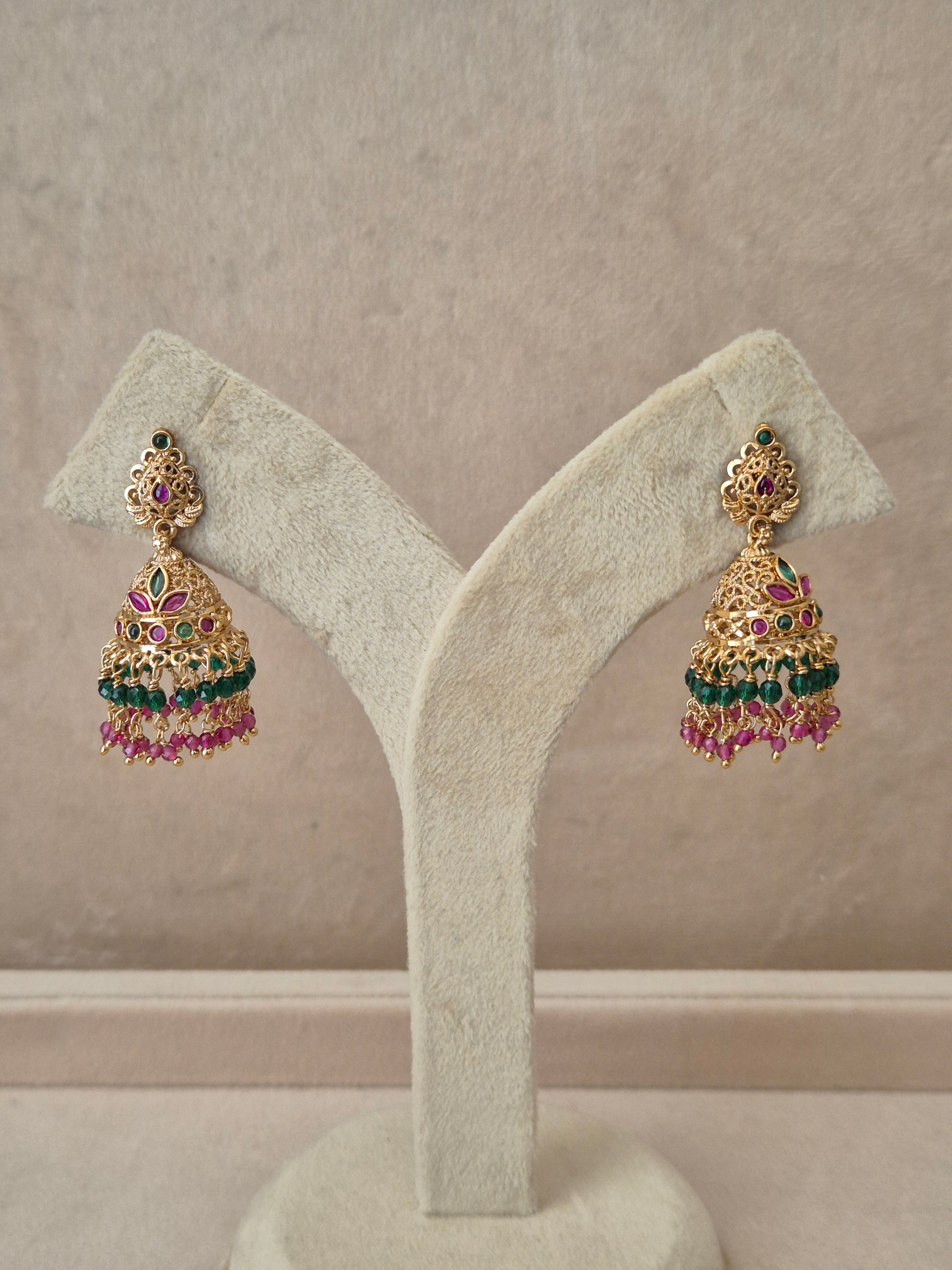 Traditional gold-toned temple design Jhumka earrings with red and green stones and colorful dangling bead fringes by naitri.in