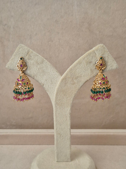 Traditional gold-toned temple design Jhumka earrings with red and green stones and colorful dangling bead fringes by naitri.in