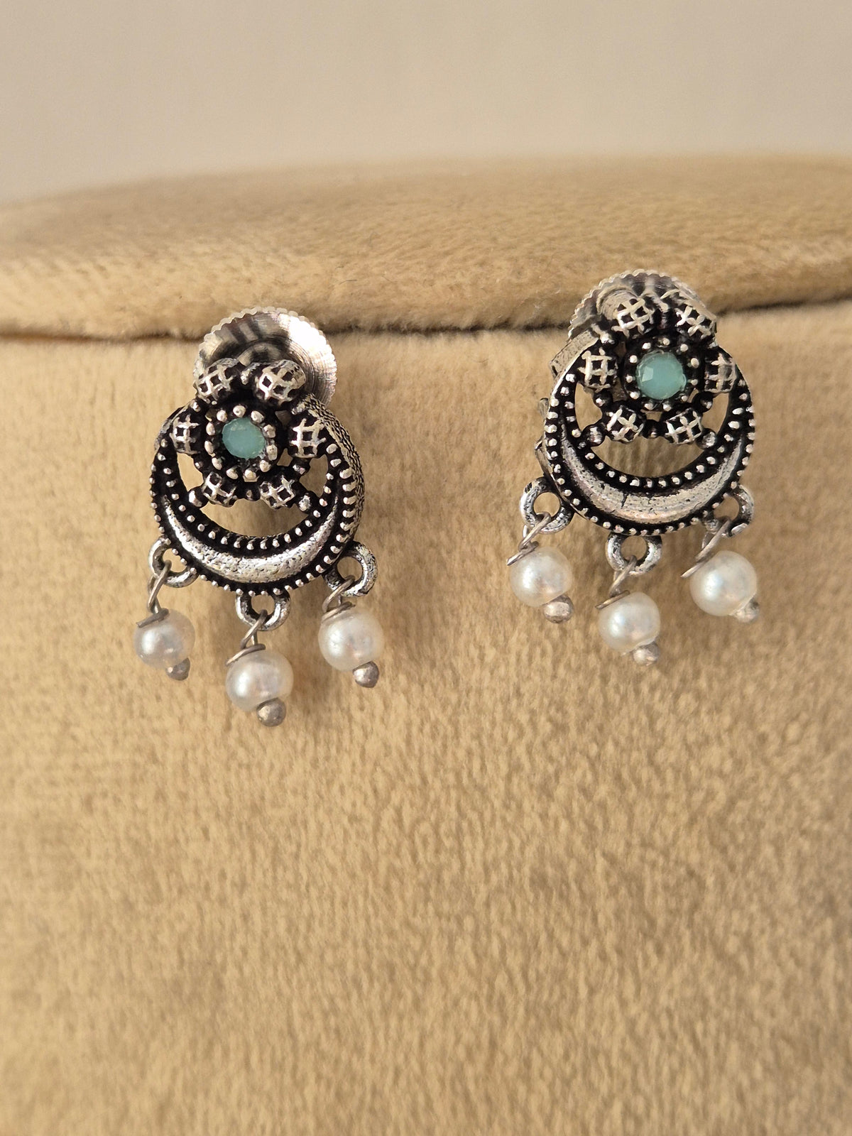 Oxidized silver earrings featuring half-circular green stone accents and dangling pearl beads, by naitri.in